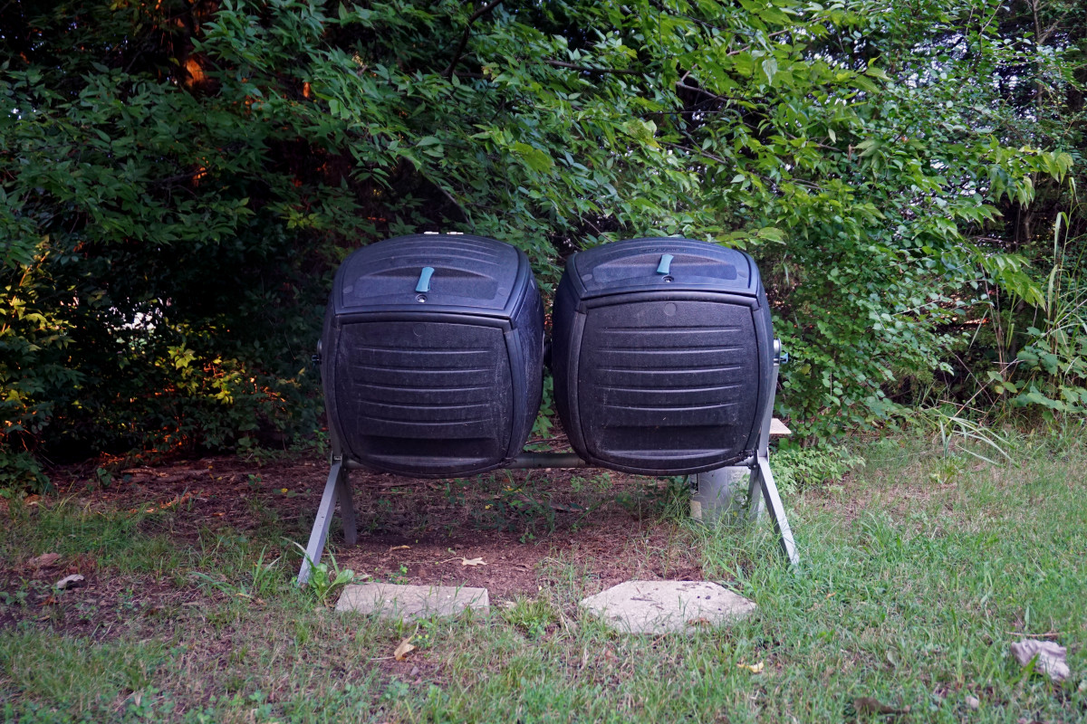 Two large tumblers outside the store hold compost material.
